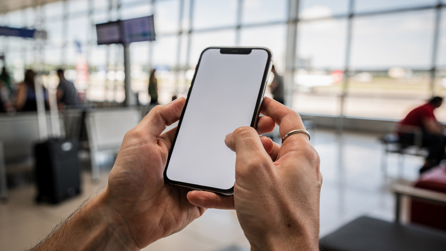 Mãos de um viajante focadas na tela do iPhone 17, escaneando um código QR para ativar um eSIM, em um saguão de aeroporto com luz natural.
