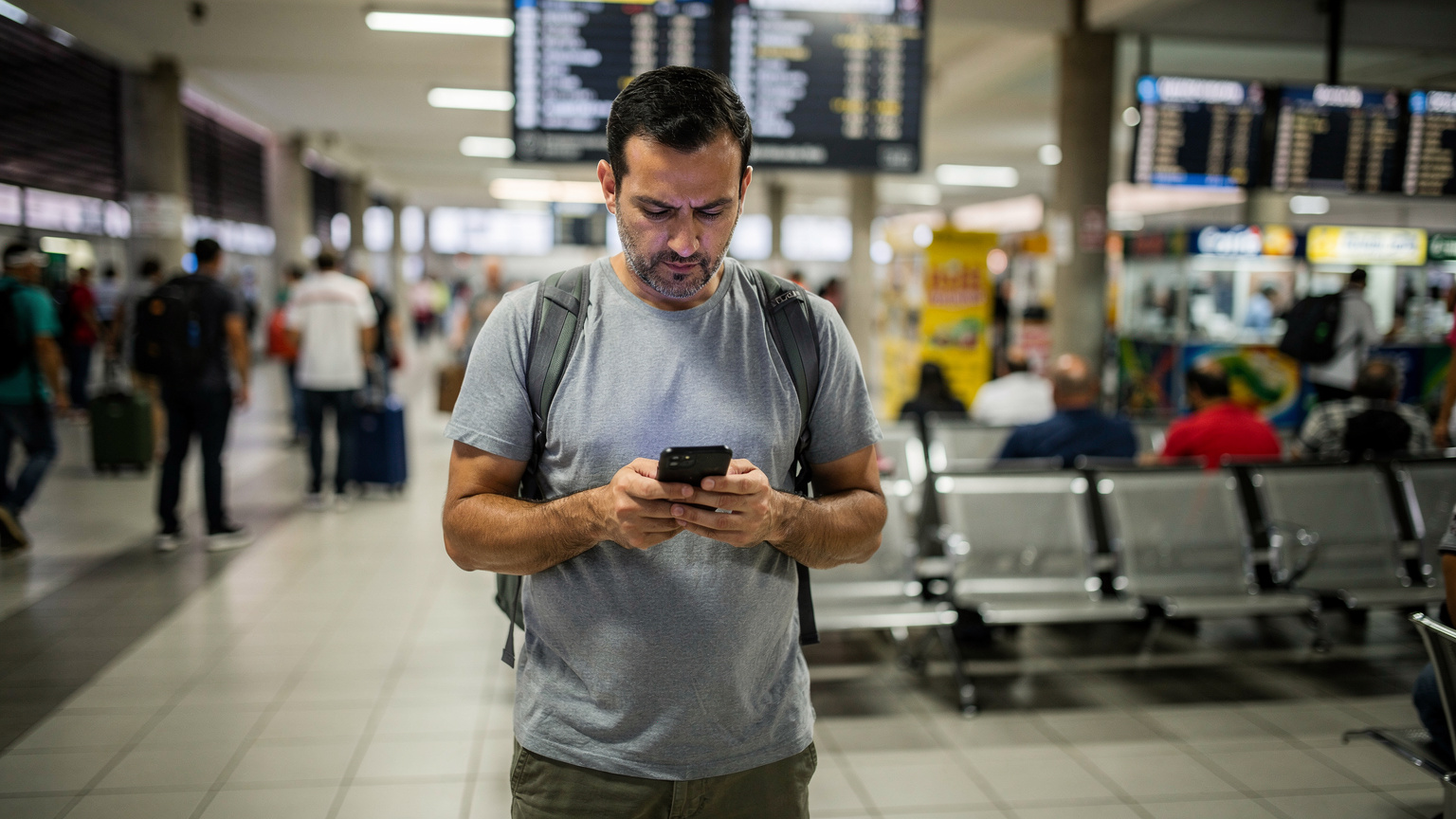 Un voyageur vérifie l'activation de son eSIM sur son smartphone dans l'agitation du terminal des bus de Rio de Janeiro.